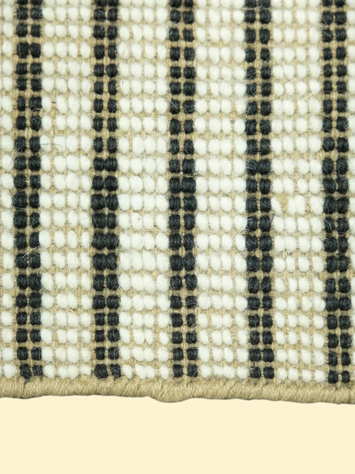 Close-up of a woven jute and wool with black, white, and beige stripes on a white background