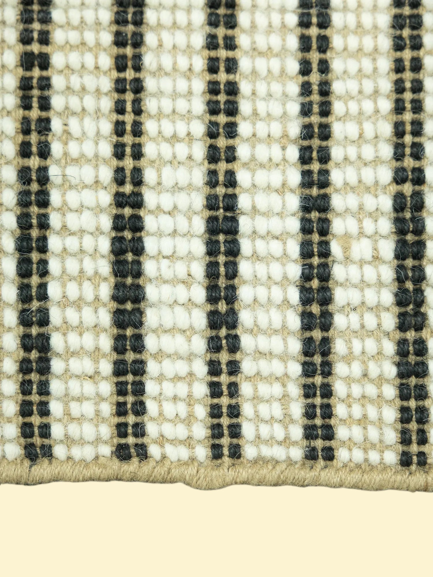 Close-up of a woven jute and wool with black, white, and beige stripes on a white background