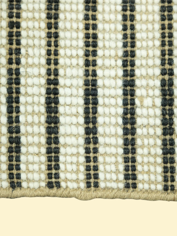 Close-up of a woven jute and wool with black, white, and beige stripes on a white background