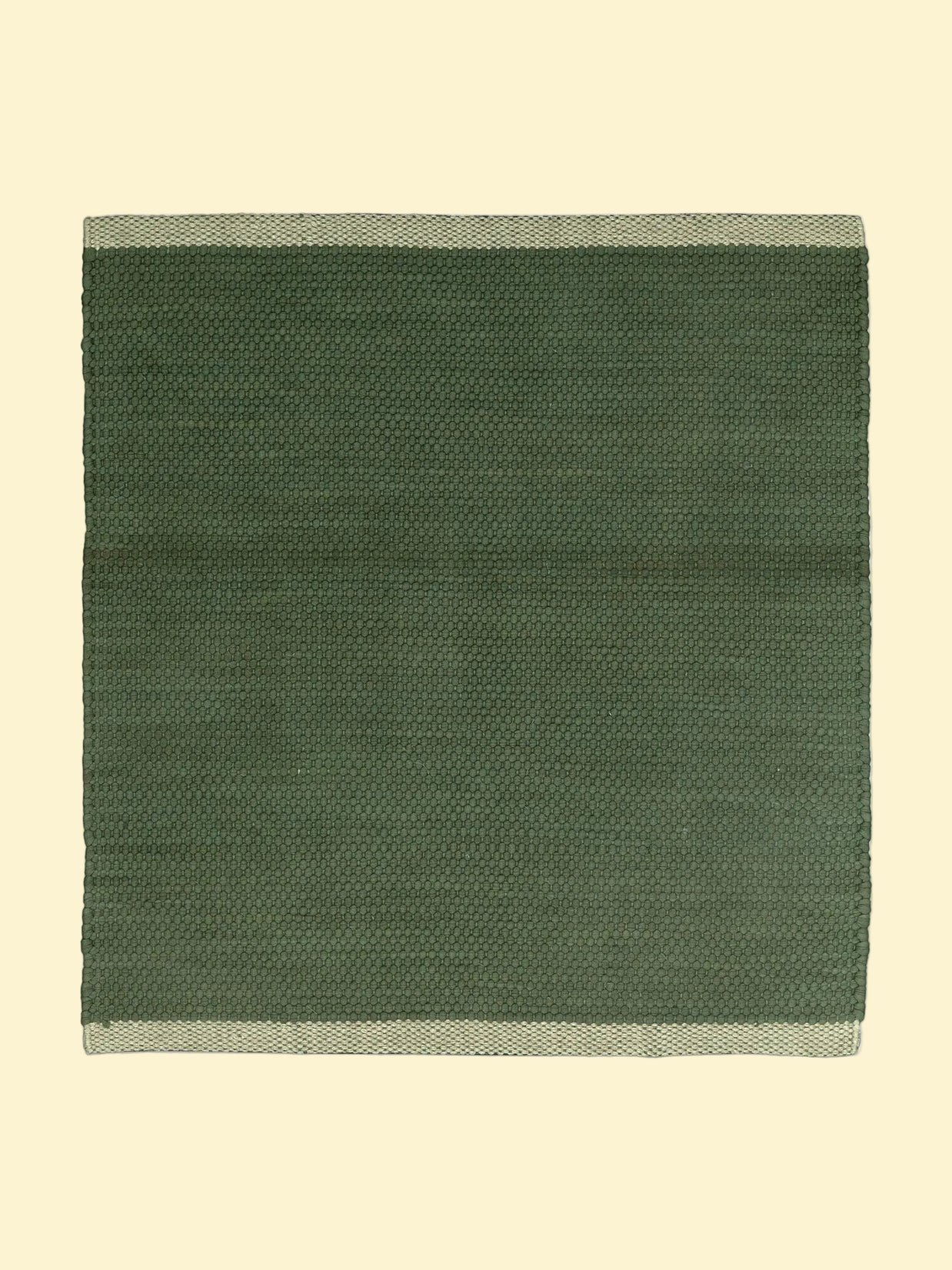 Green woven cotton durrie with a natural  beige border