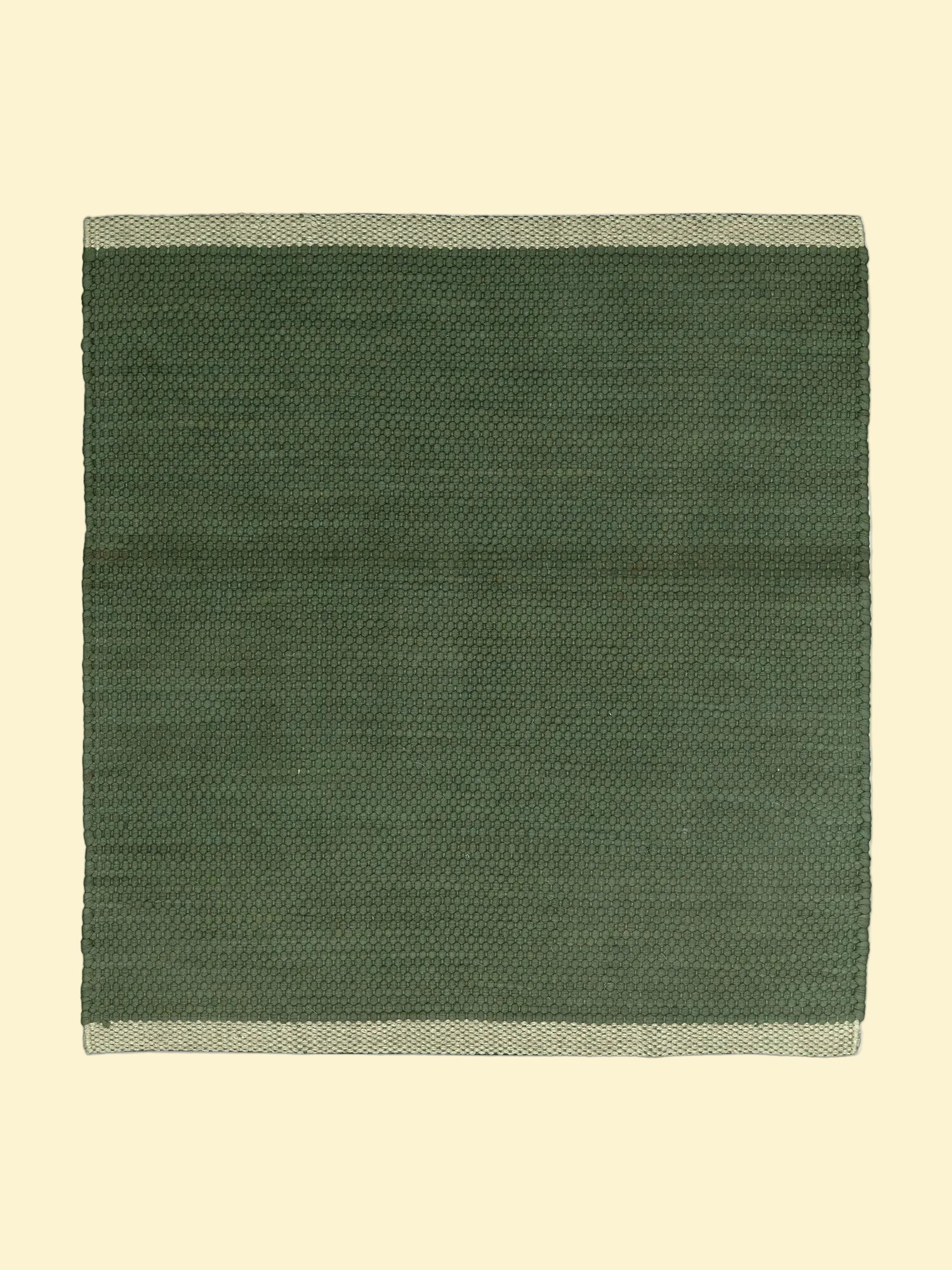 Green woven cotton durrie with a natural  beige border