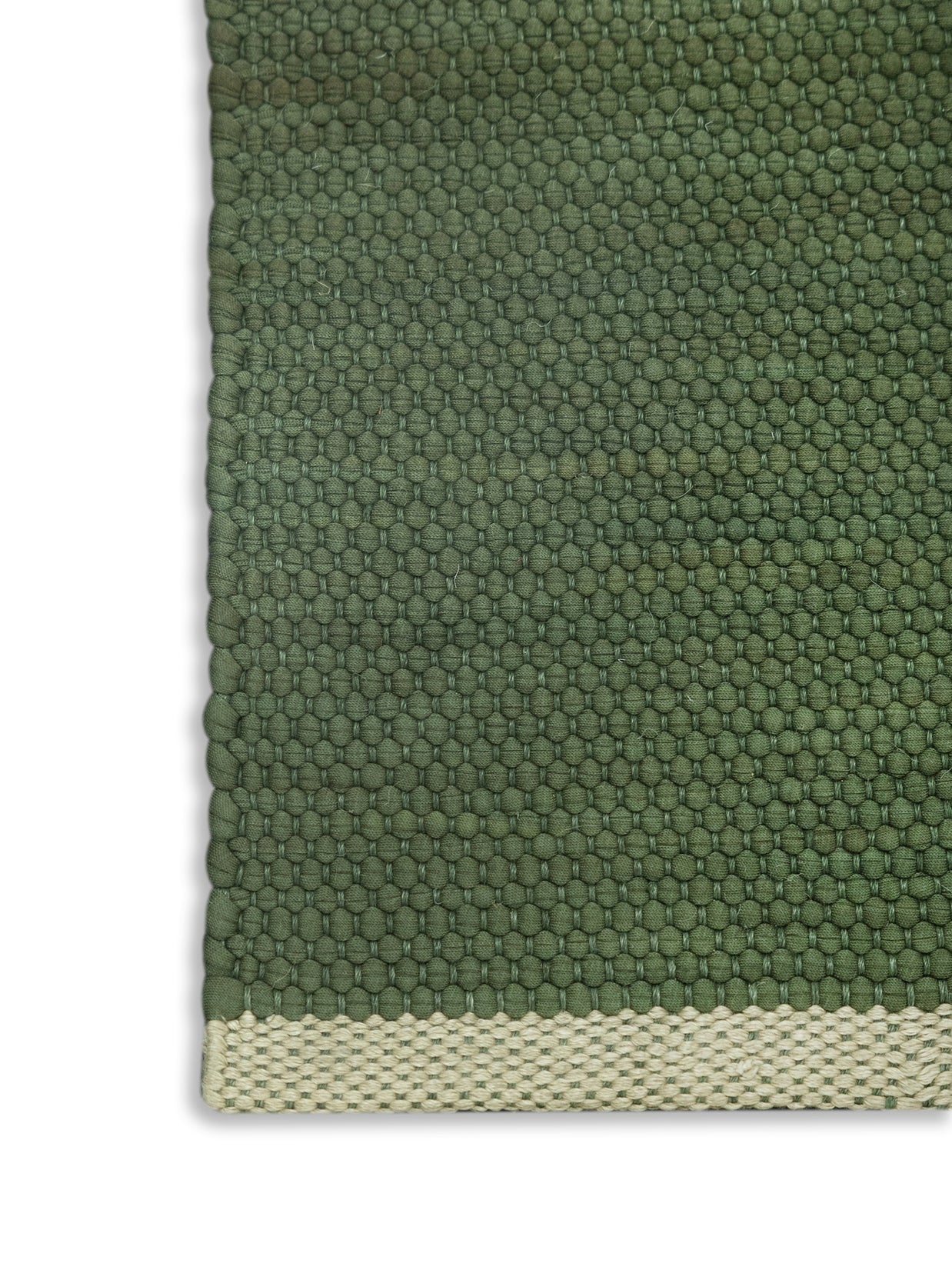 Close-up of a green textured rug with a beige border highlighting the corner detail